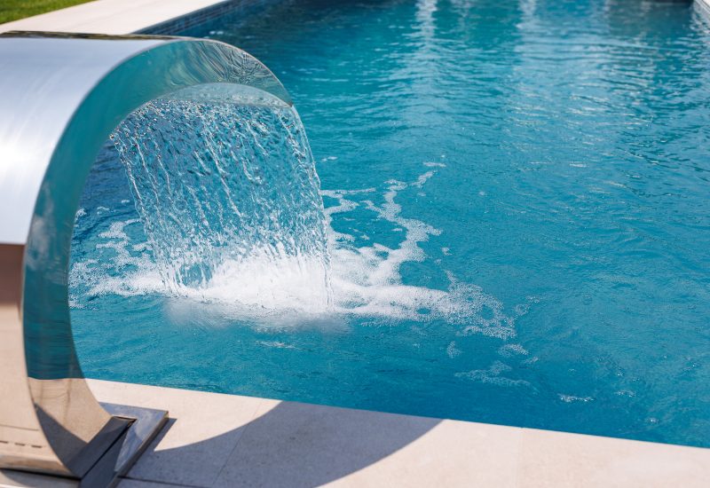 Modern water feature pouring into pool, showcasing a unique water design in Jacksonville, FL