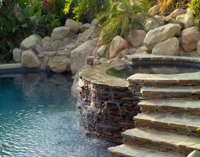 Stone structure with a waterfall into a pool, showcasing unique water features in Jacksonville, FL